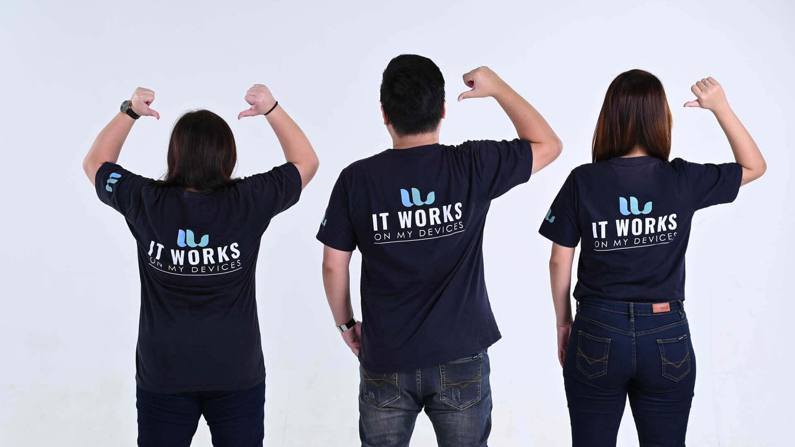 Three Winnefy team members pointing at their shirts, which read It Works On My Devices